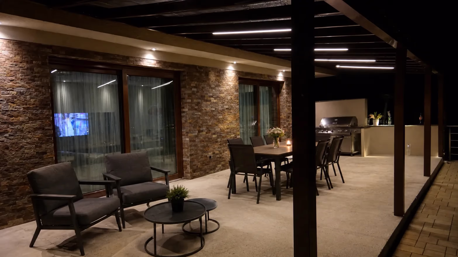 Holzpergola mit integrierter LED-Streifenbeleuchtung über einer nächtlichen Terrasse mit Esstisch