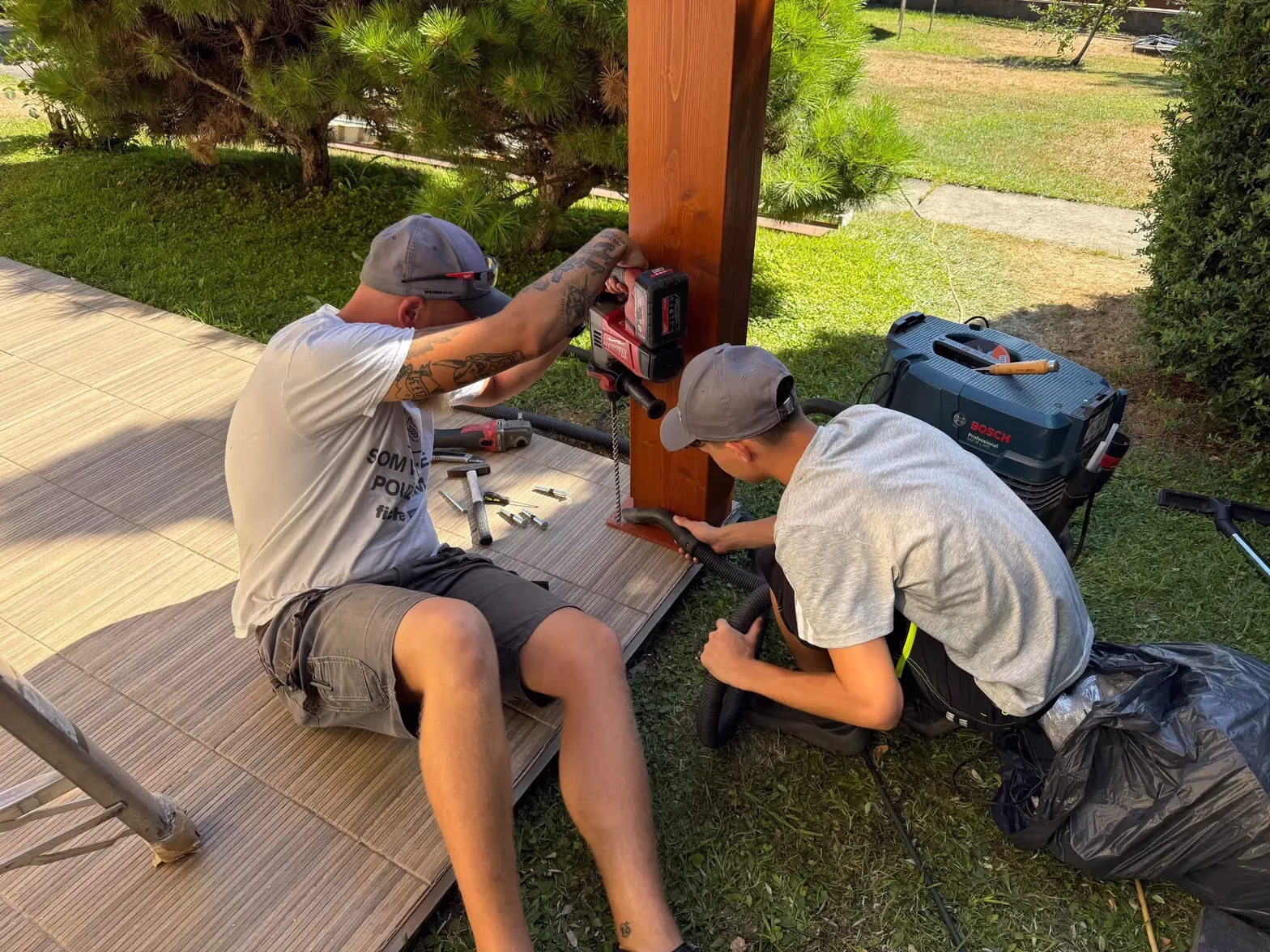 Monteure bohren Verankerungslöcher in den Tragpfosten einer Holzpergola