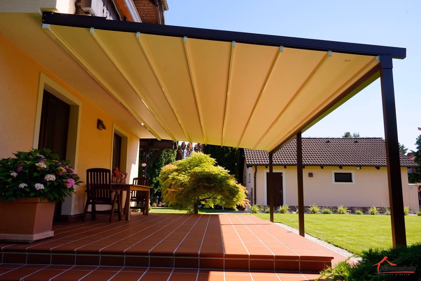 Moderne Aluminiumpergola Solaris mit Beschattungsvorhang neben einem Haus