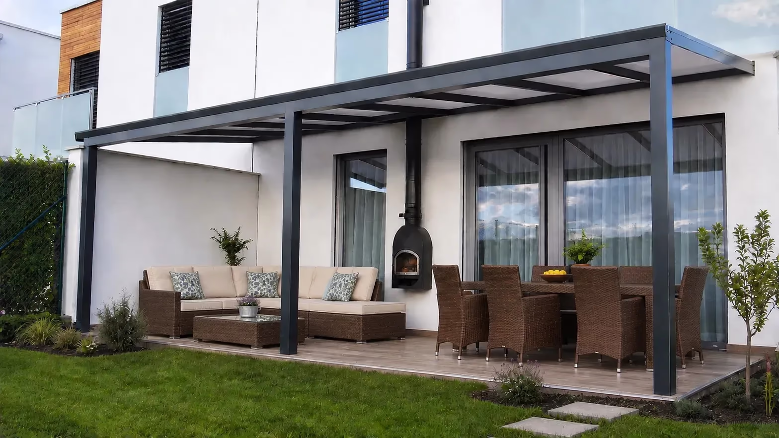 Anthrazitfarbene Aluminiumpergola über einer Terrasse mit Esstisch und Außenofen