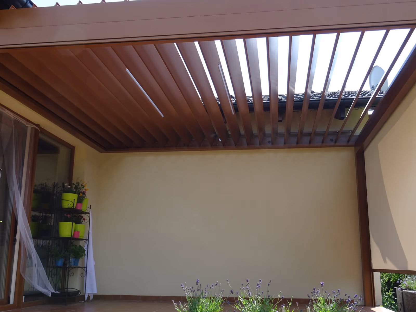 Bioklimatische Aluminiumpergola mit drehbaren Lamellen neben einem modernen Neubau