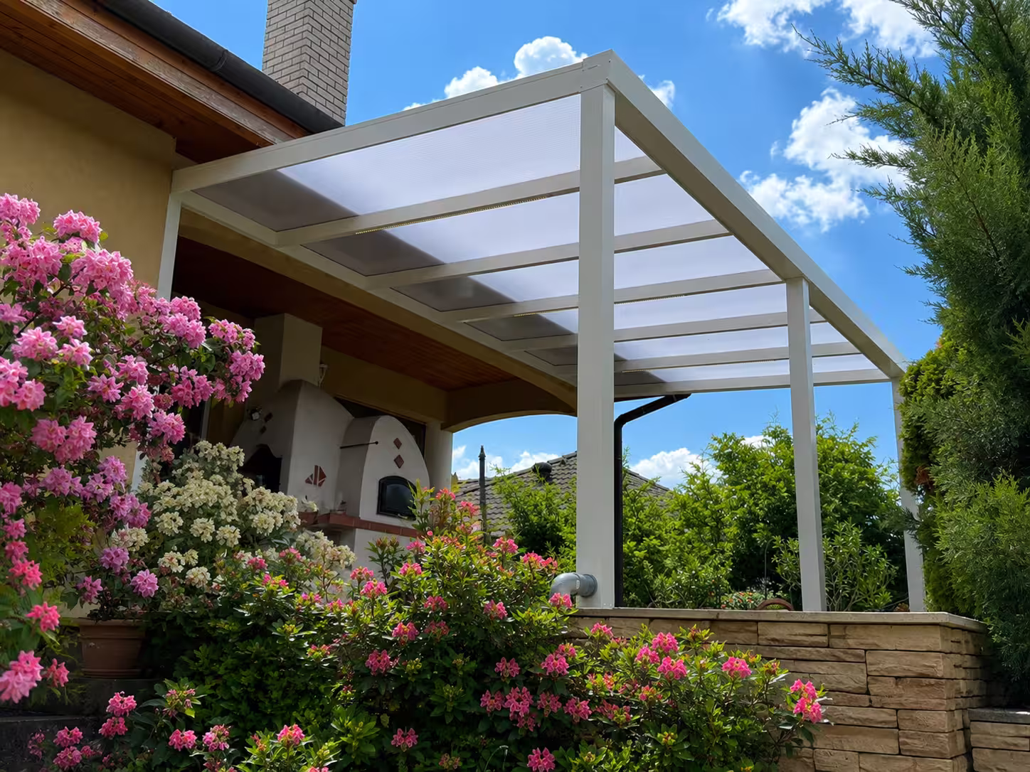 Weiße Aluminiumpergola Economic Class in einem blühenden Garten
