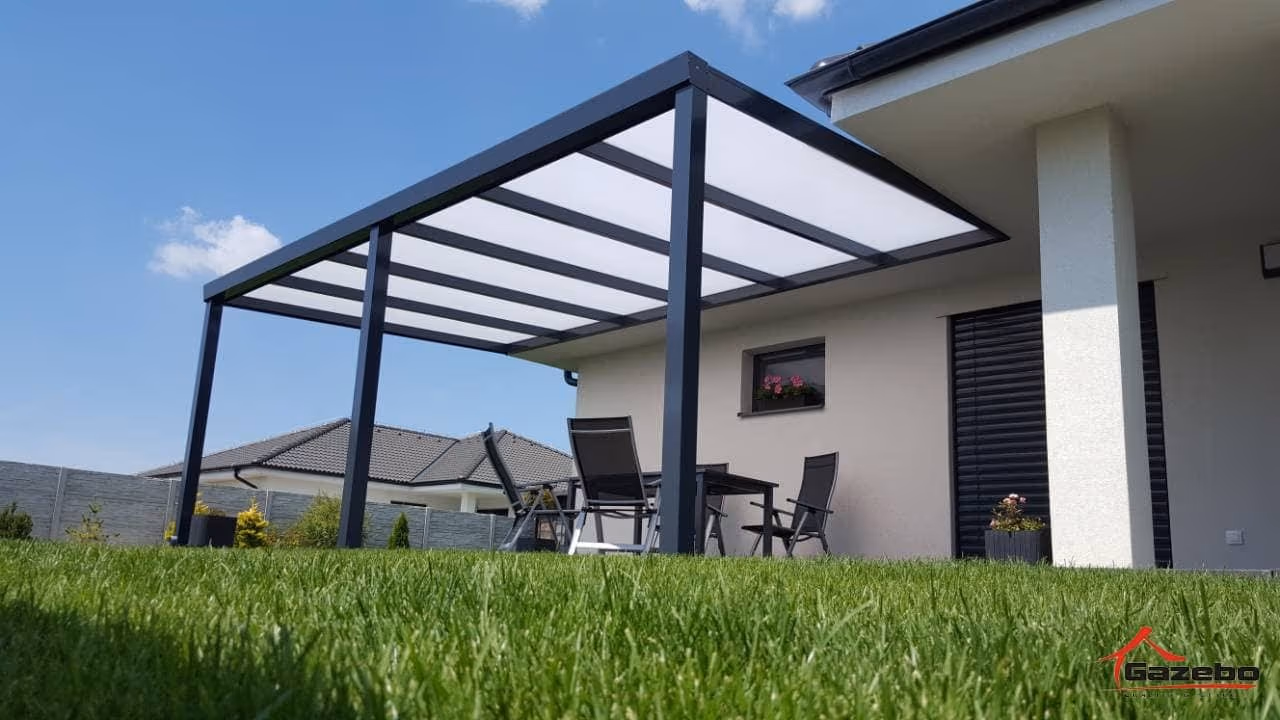 Anthrazitfarbene Aluminiumpergola Economic Class an einem weißen Haus mit Sitzplatz auf der Terrasse und Rasen