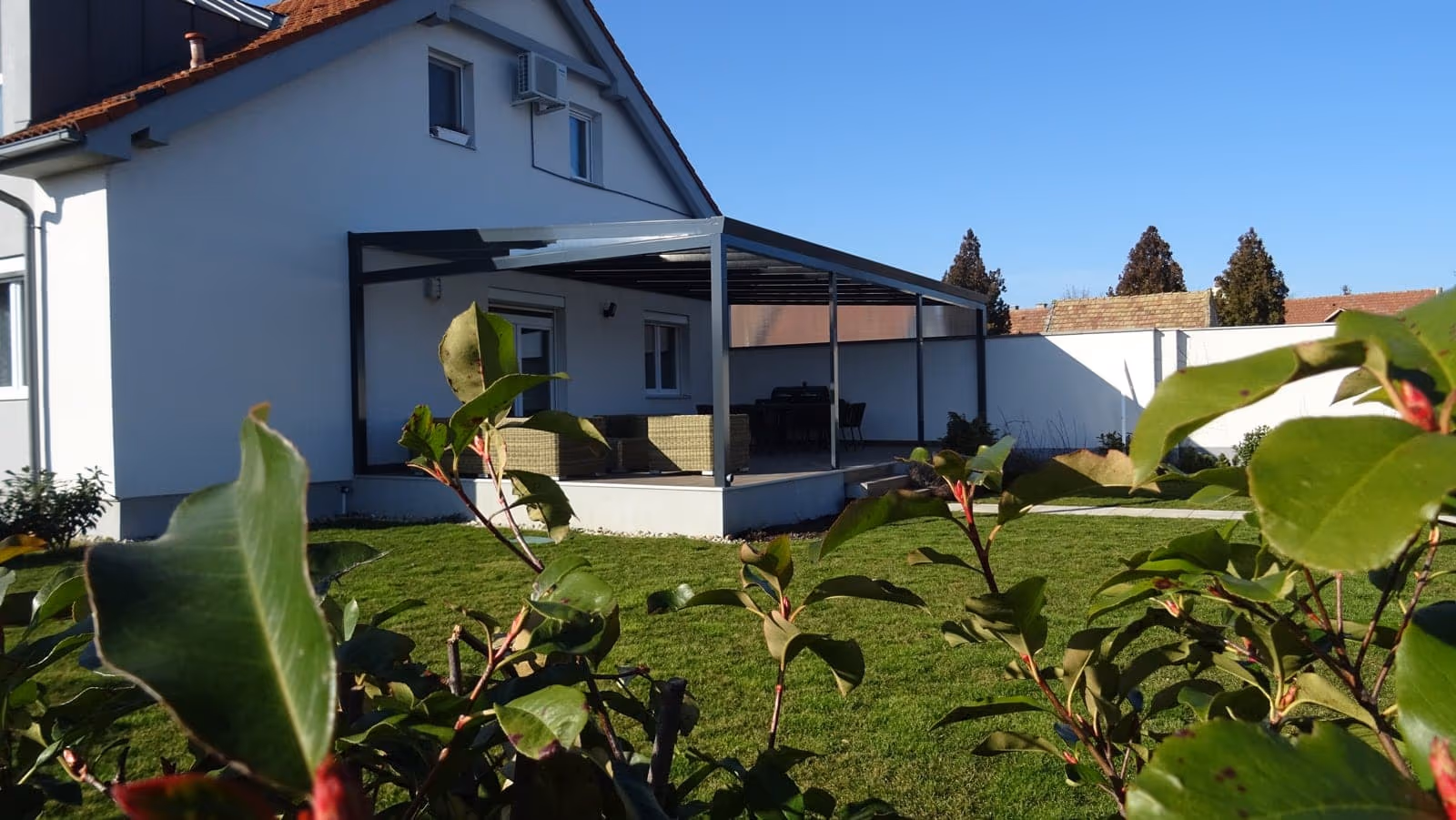Aluminiumpergola Economic Class bei einem Haus mit Schrägdach und großem Fenster