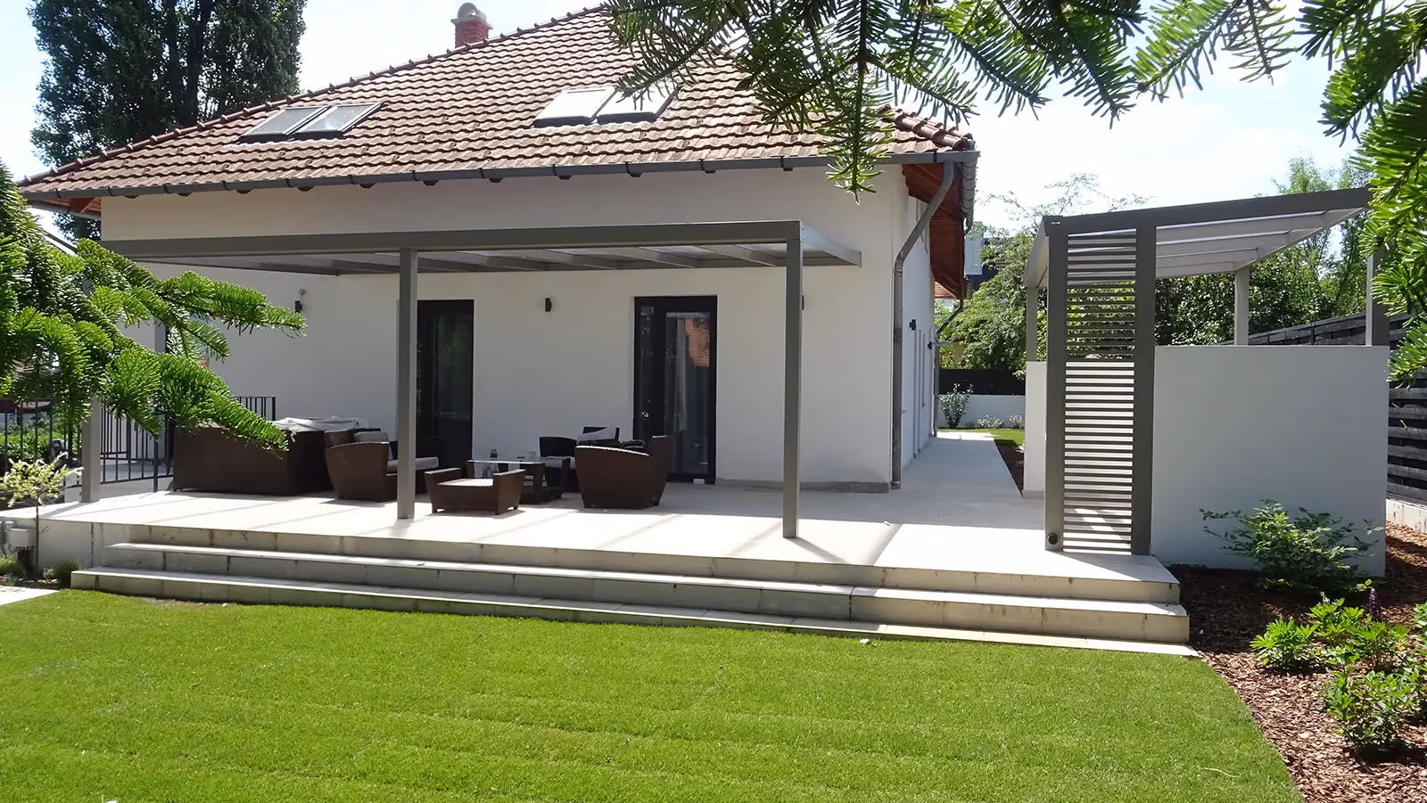 Aluminiumpergola Economic Class mit bequemer Sitzgelegenheit auf einer Holzterrasse