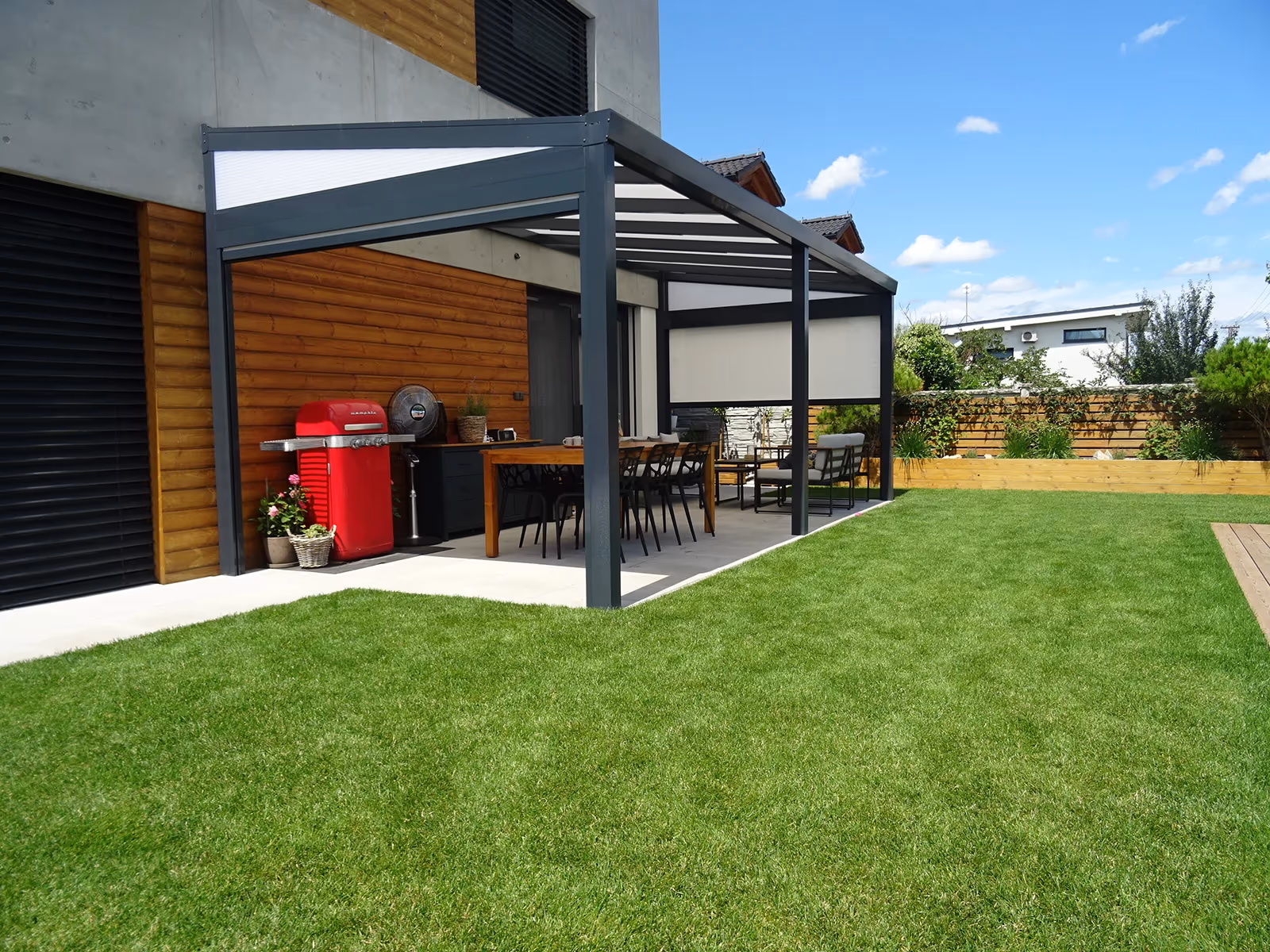 Nachts beleuchtete Aluminiumpergola Economic Class vor einer Ziegelfassade