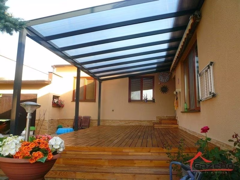 Anthrazitfarbene Aluminiumpergola Economic Class über einer Holzterrasse mit Heizstrahler und Blumen