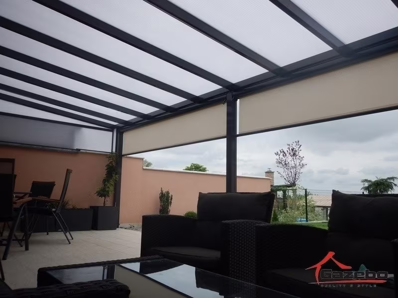 Anthrazitfarbene Aluminiumpergola Economic Class über einer Terrasse mit Rattan-Loungemöbeln