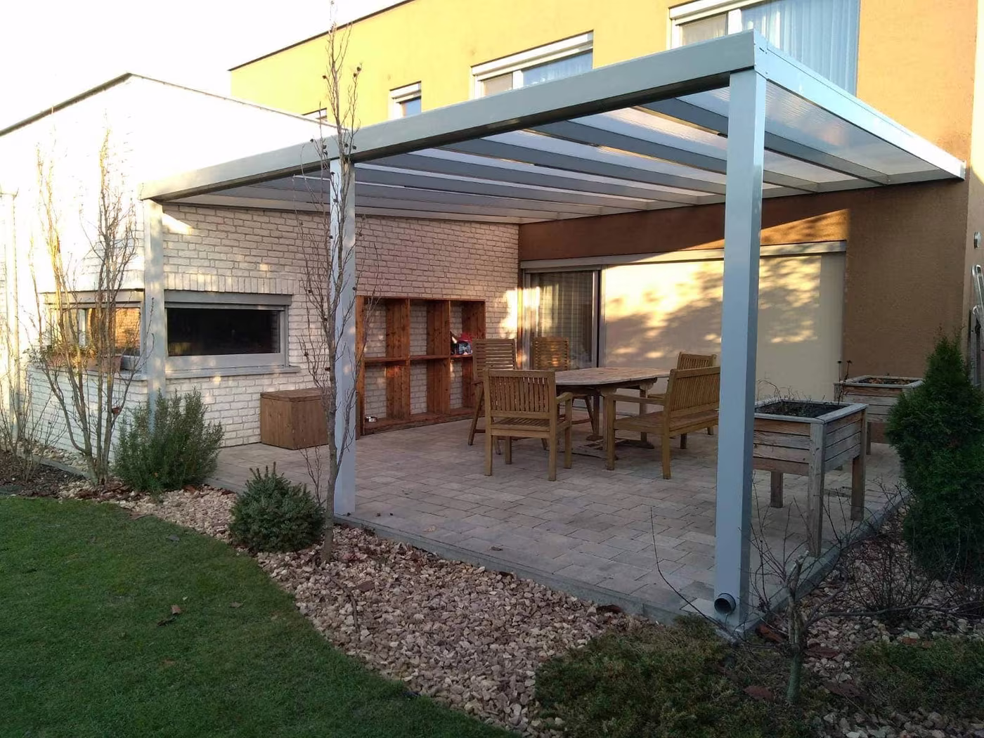 Silberne Aluminiumpergola Economic Class über einer Kiesfläche mit Essgruppe