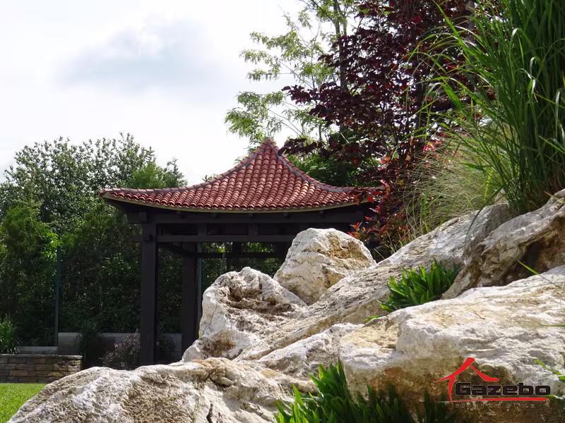 Holzpavillon Hinode zwischen Ziersteinen und Gräsern