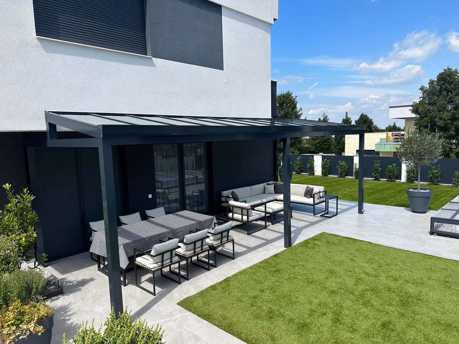 Aluminiumpergola Top Class mit bunten Kissen bei einem modernen Haus