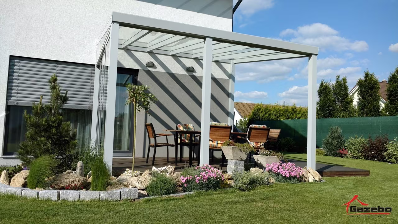 Weiße Aluminiumpergola Top Class über einer Terrasse mit Essgruppe und gepflegtem Garten