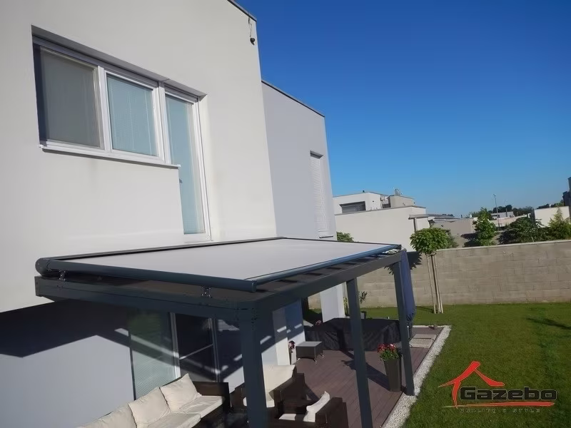 Anthrazitfarbene Aluminiumpergola Top Class mit Frontbeschattung auf einer Terrasse an einem modernen weißen Haus