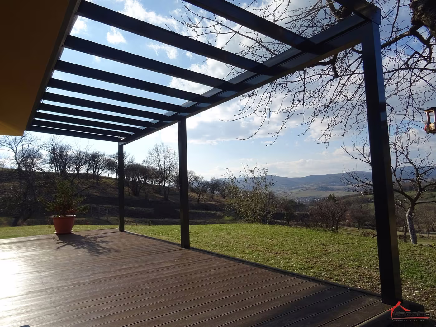 Anthrazitfarbene Aluminiumpergola Top Class über einer Holzterrasse mit Blick in die Landschaft