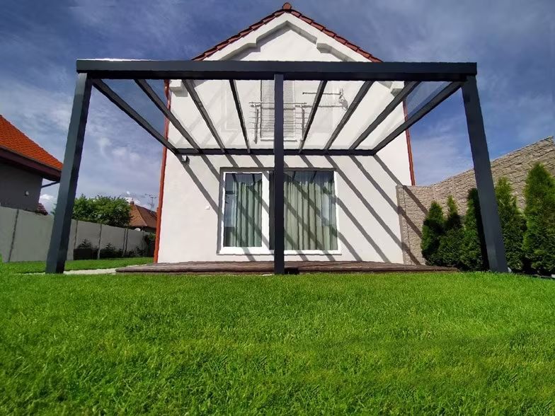 Anthrazitfarbene Aluminiumpergola Top Class an einem weißen Satteldachhaus mit verglasten Türen
