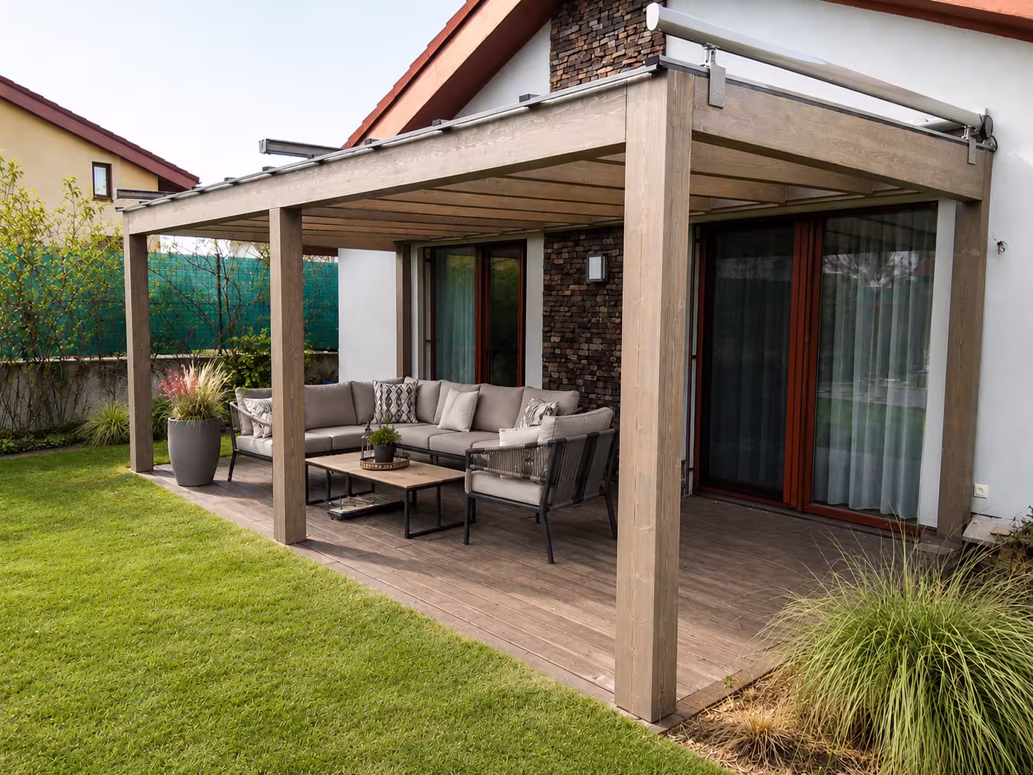 Holzpergola Milano an einer Steinfassade mit grauer Sitzgruppe