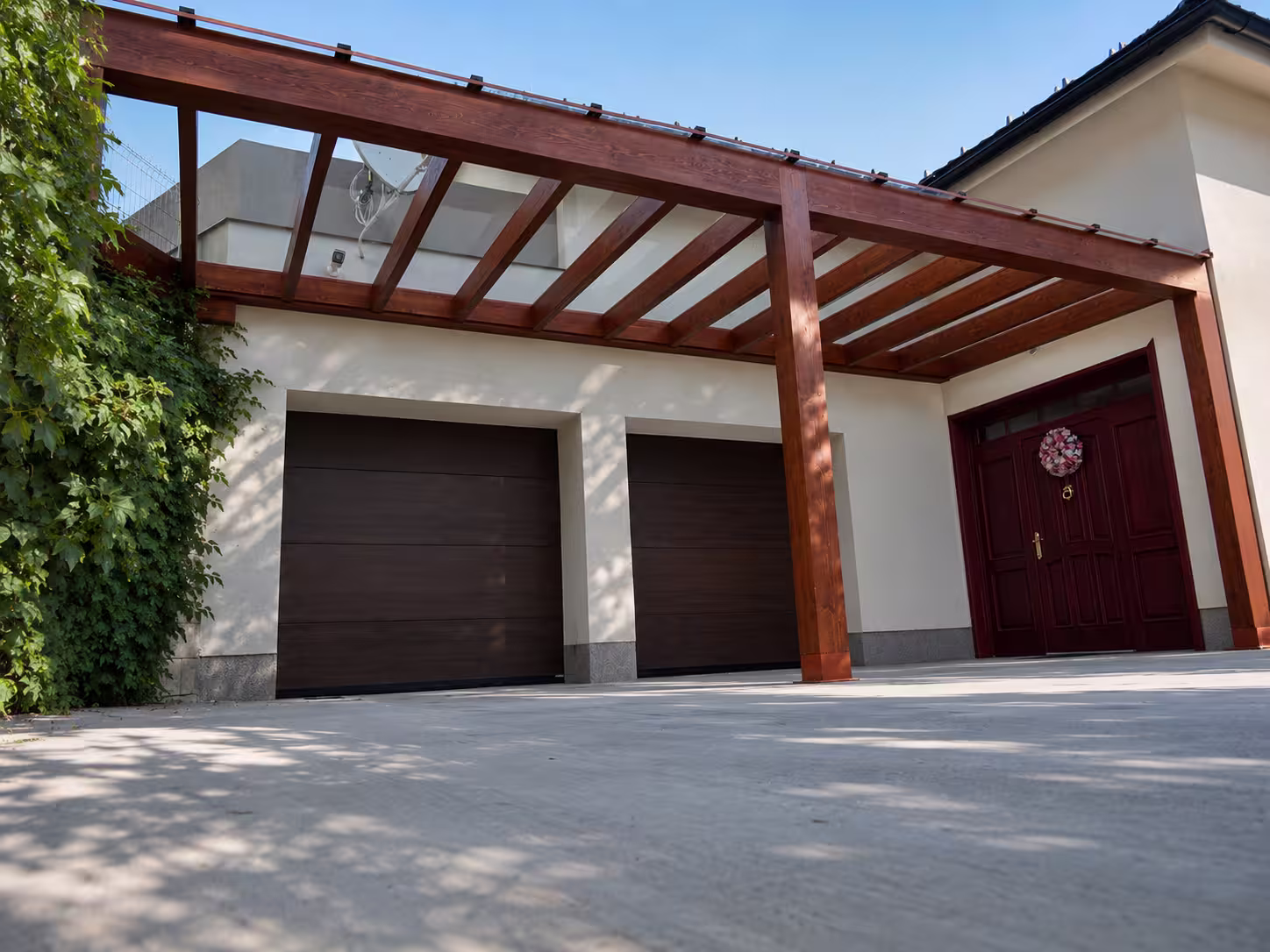 Holzpergola Milano mit verglastem Dach neben einer Garage