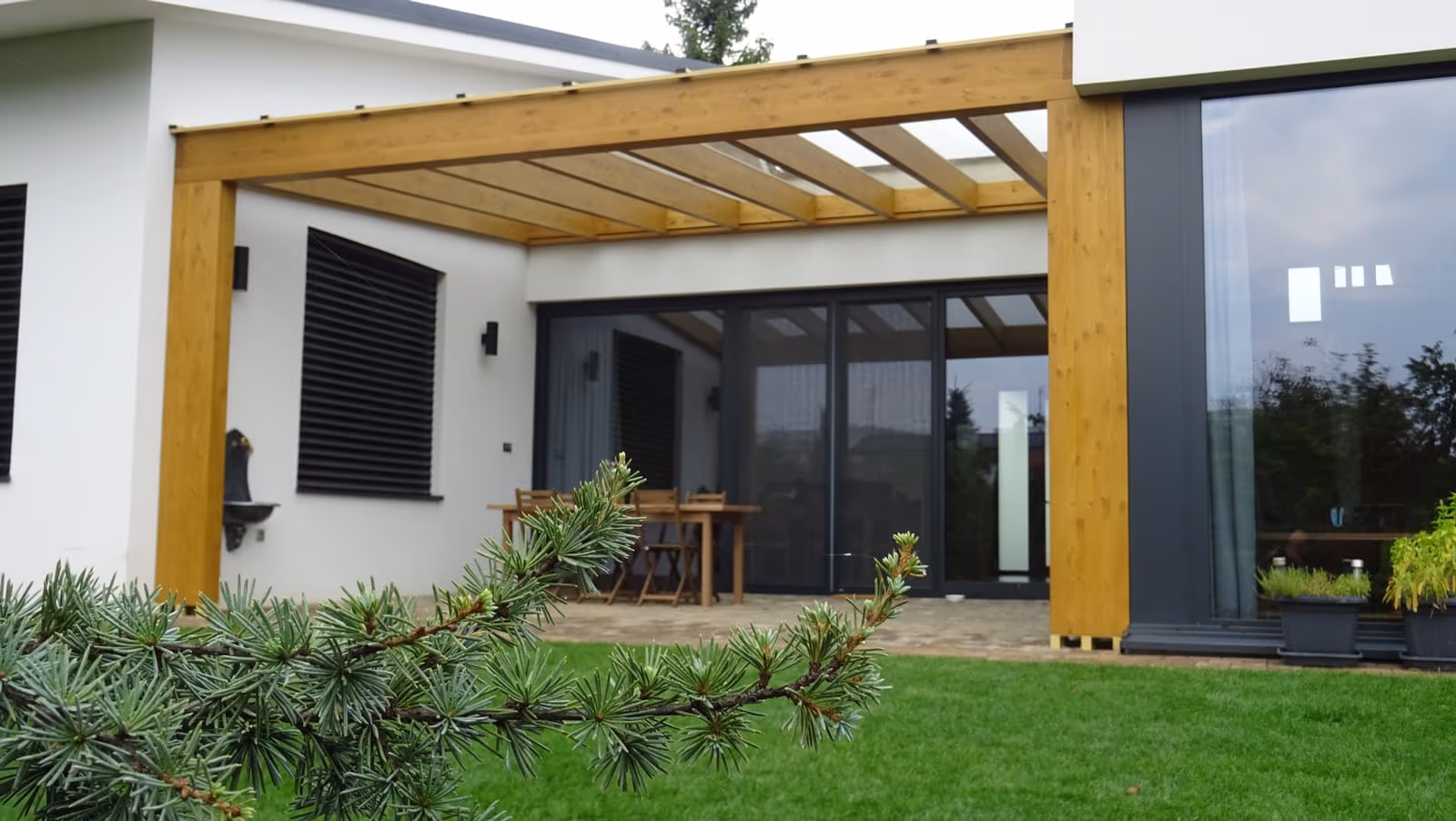Holzpergola Milano in hellem Holzton über einem Essplatz