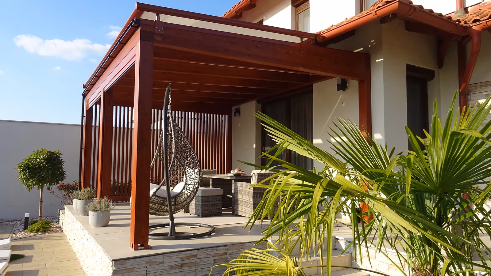 Holzpergola Milano mit Hängesessel und Palme