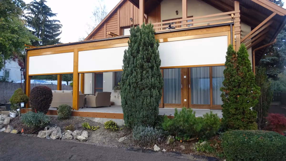Holzpergola Milano zwischen Nadelbäumen auf der Terrasse
