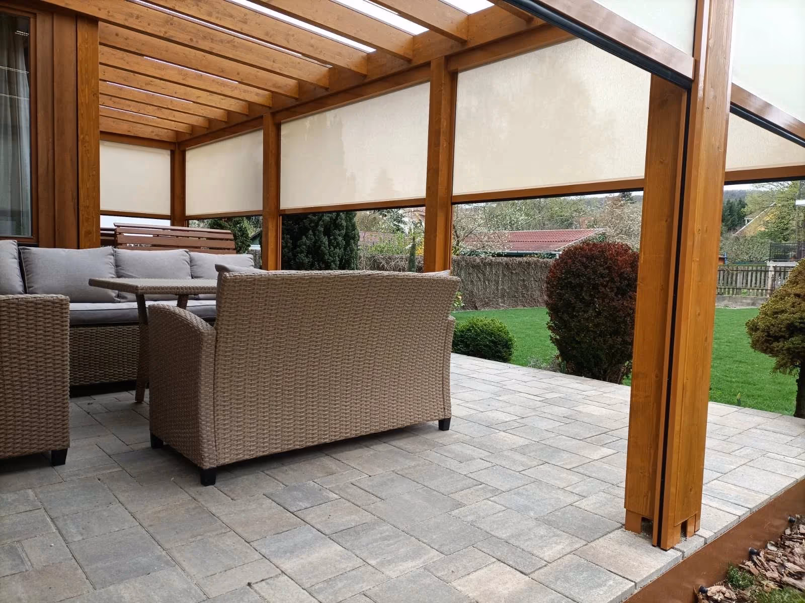 Holzpergola Milano mit bequemer Sitzgelegenheit auf gepflasterter Terrasse