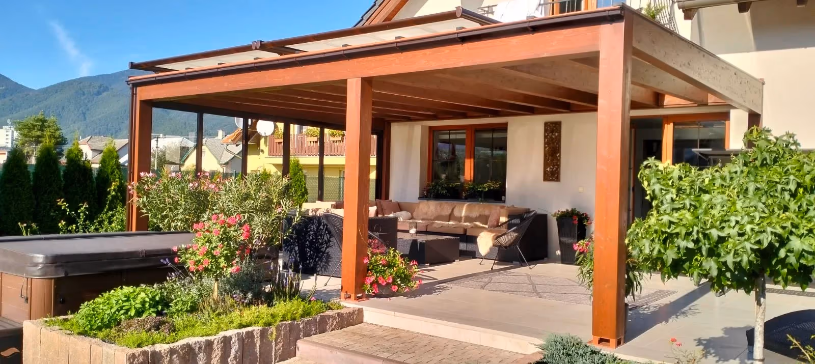 Holzpergola Milano mit Sitzgruppe bei einem dunkel gehaltenen Einfamilienhaus