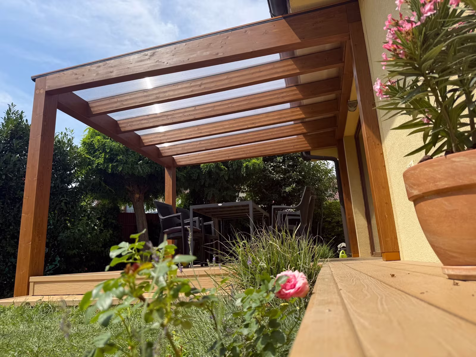 Holzpergola Milano mit transparentem Polycarbonatdach an der Terrasse eines Einfamilienhauses