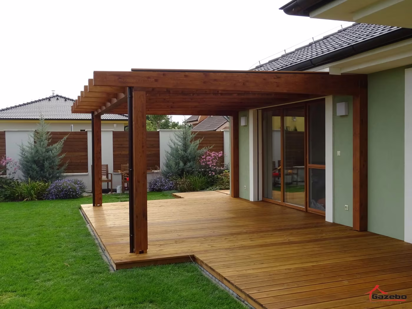Holzpergola Fenix über einer erhöhten Holzterrasse an einem Einfamilienhaus